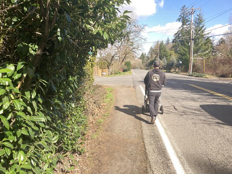 Person pushing stroller along SW Boones Fery Rd narrow dangerous shoulder.
